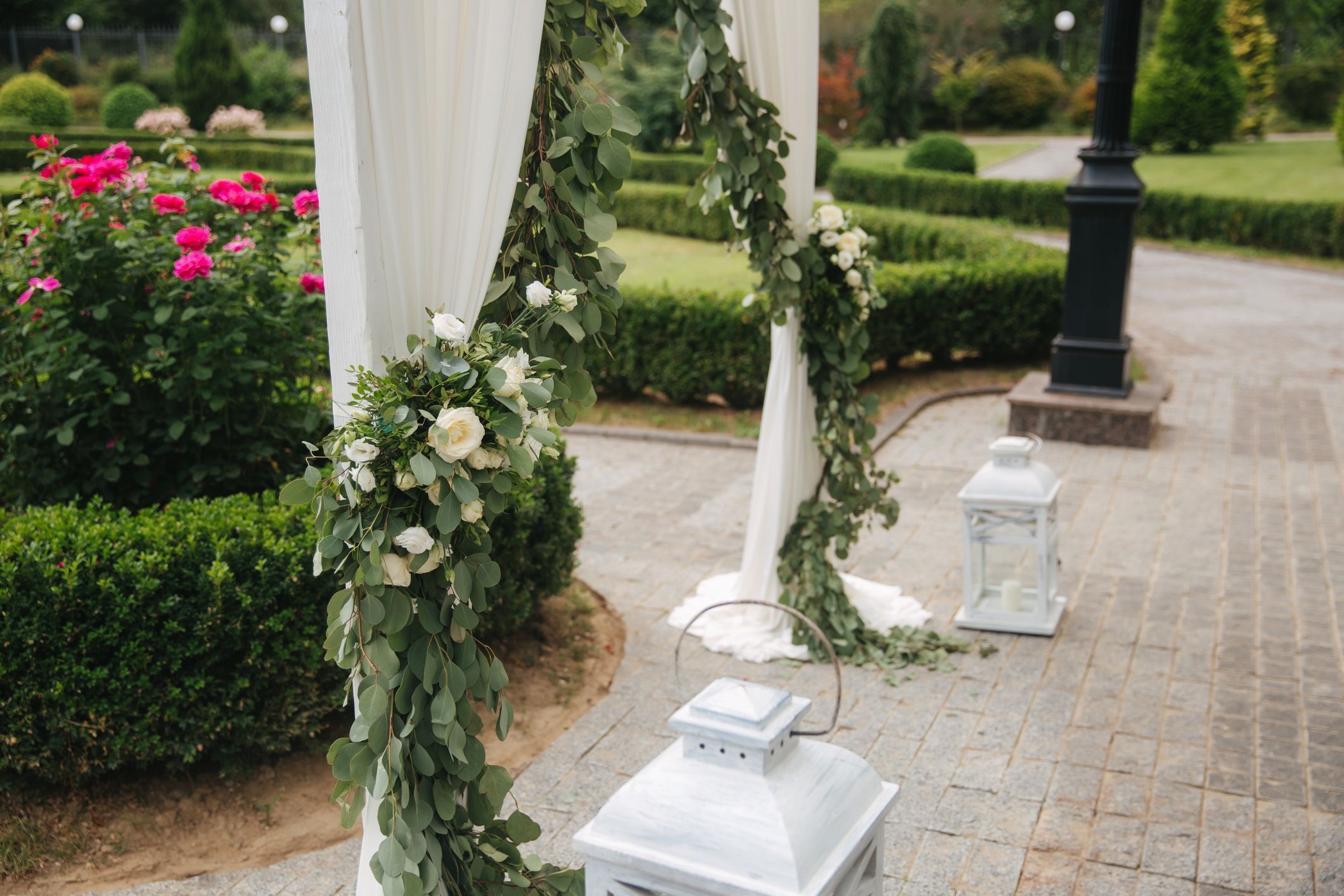 Weddind decoration on open air. Floral decor of a beautiful white arch. Beautiful beckground view of trees Weddind decoration on open air. Floral decor of a beautiful white arch. Beautiful beckground view of trees.
